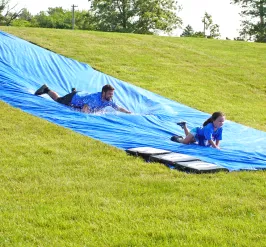 Photo of a father and daughter going down a slip 'n slide at the Youth Sports Adventure Run