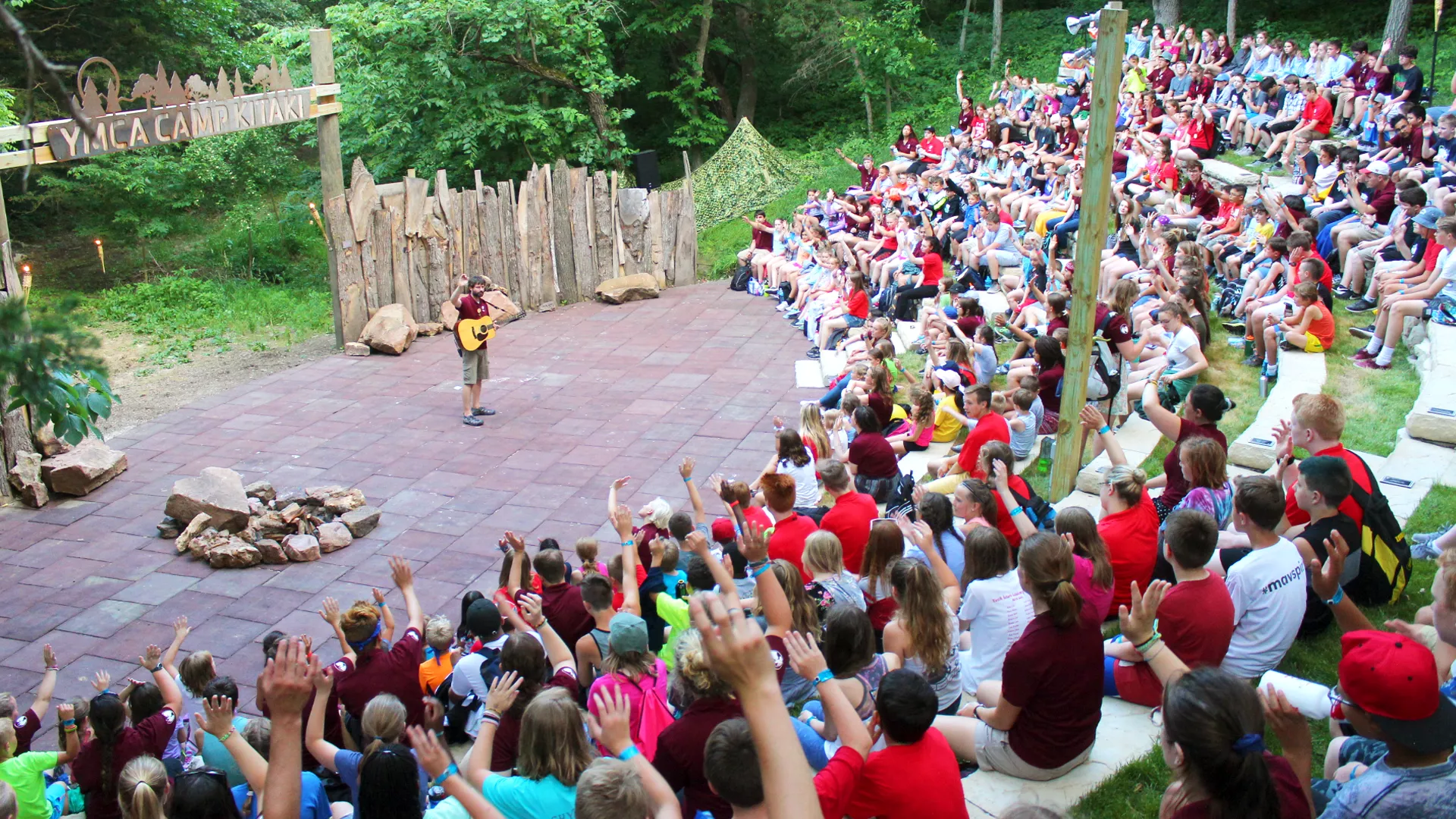 Group of kids cheer and sing during a camp fire at Camp Kitaki.