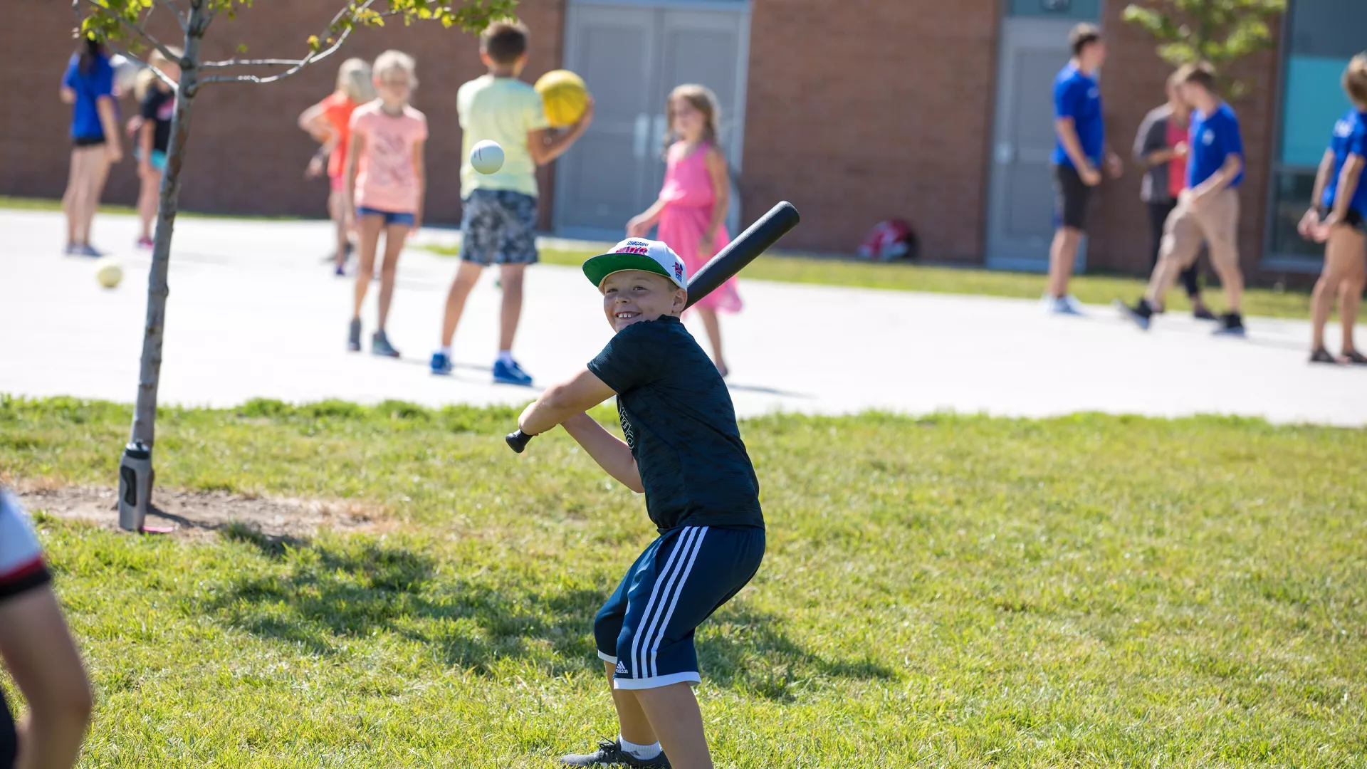 Boy smiles as he gets ready to bat during a game of baseball at day camp.