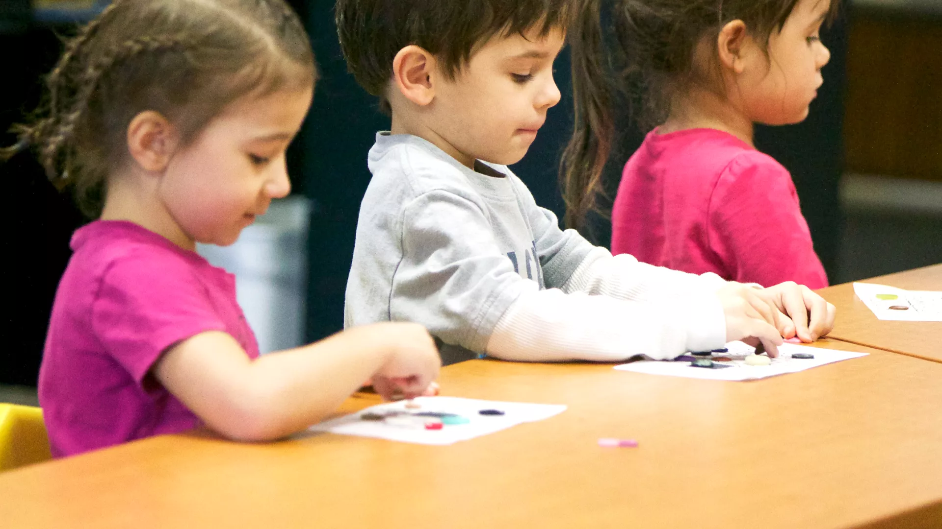 Children sit and work on a craft during preschool.