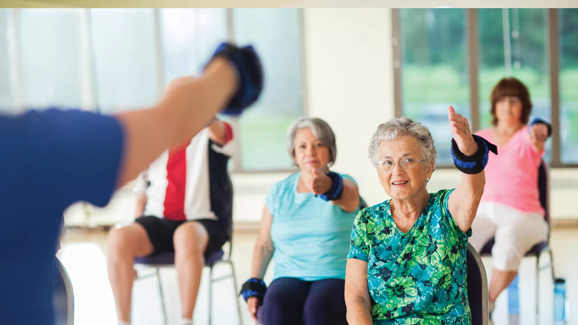Older adults smile during their chair workout class.