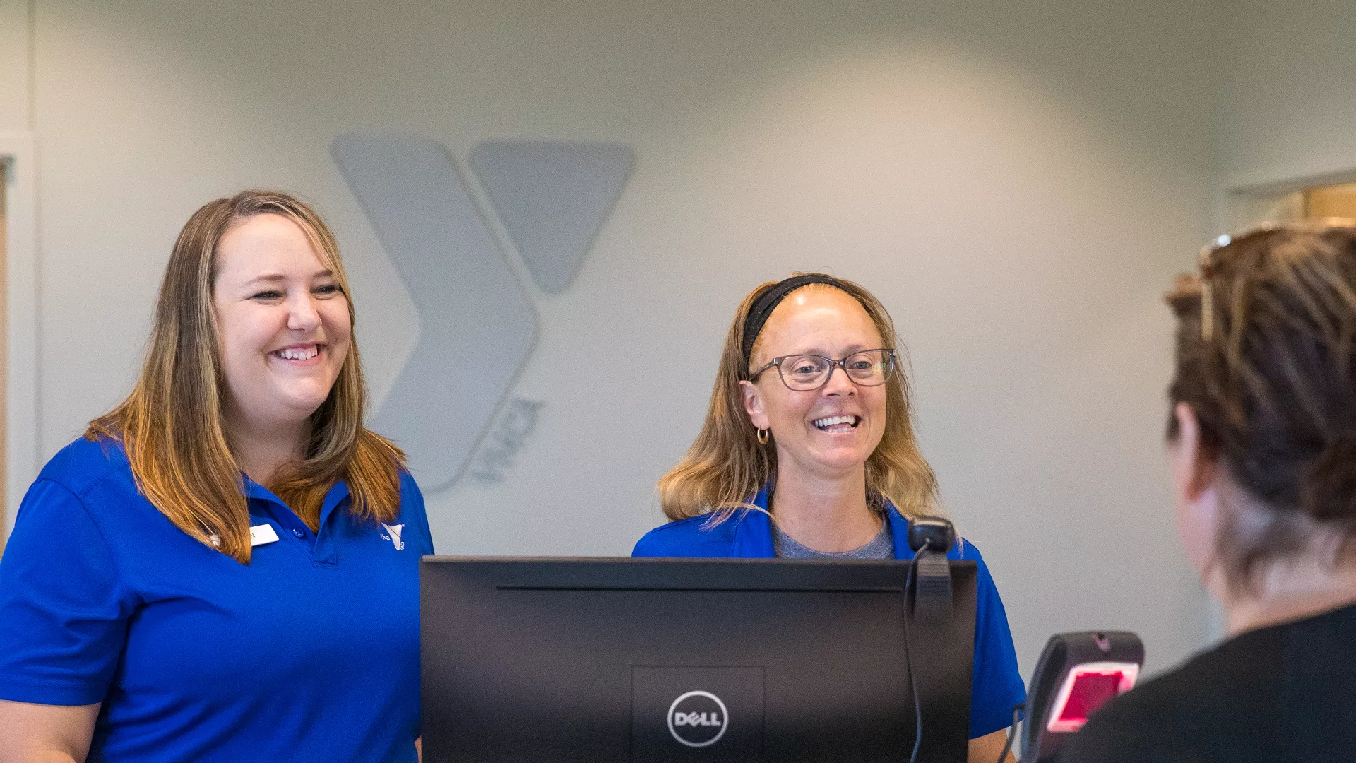 Front desk staff smile as they greet a member.