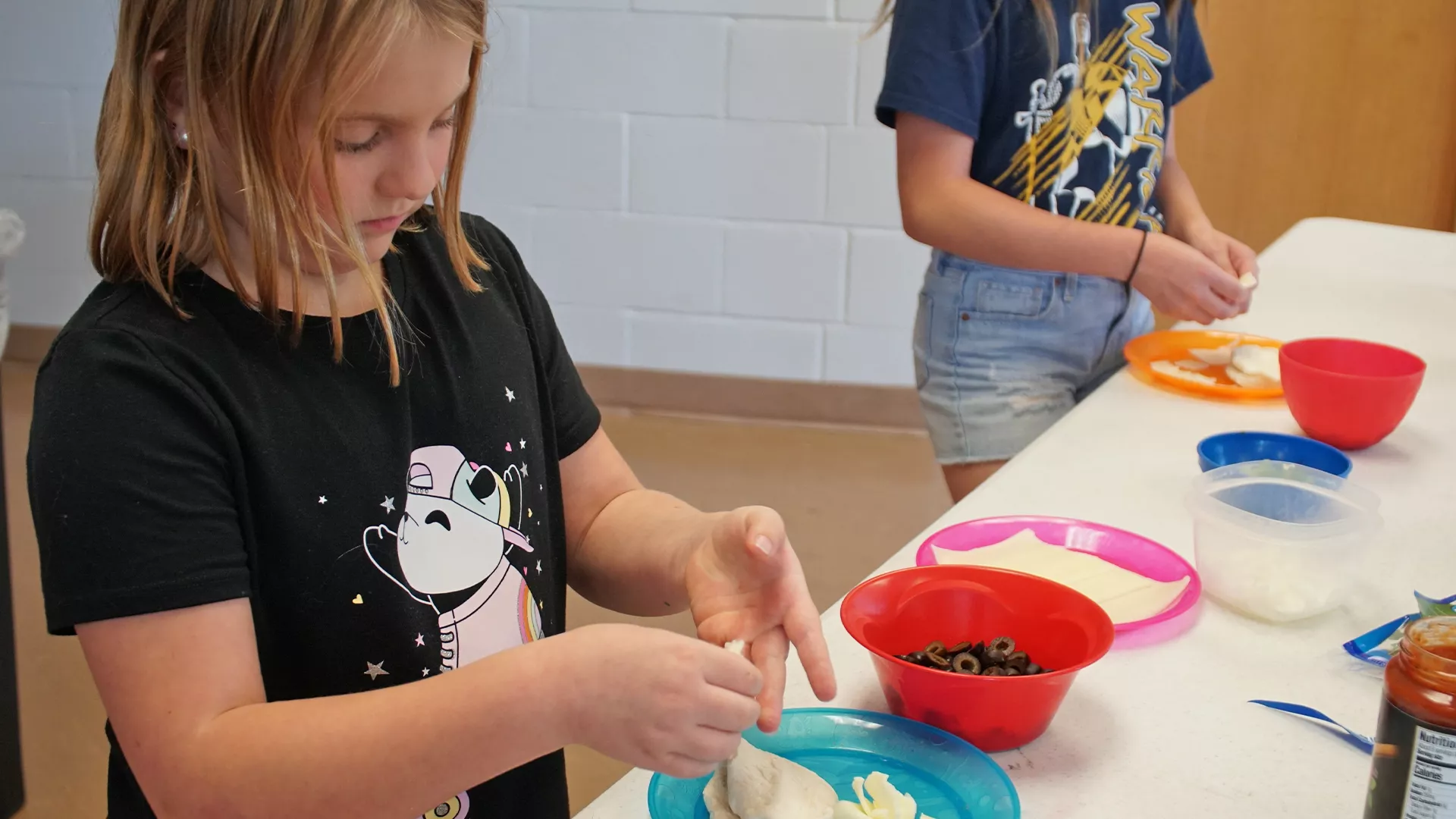 A girl making a pizza pocket in Jr. Chefs