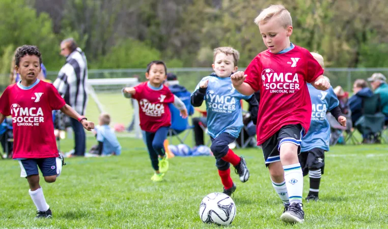 Group of boys run after the soccer ball during a game.