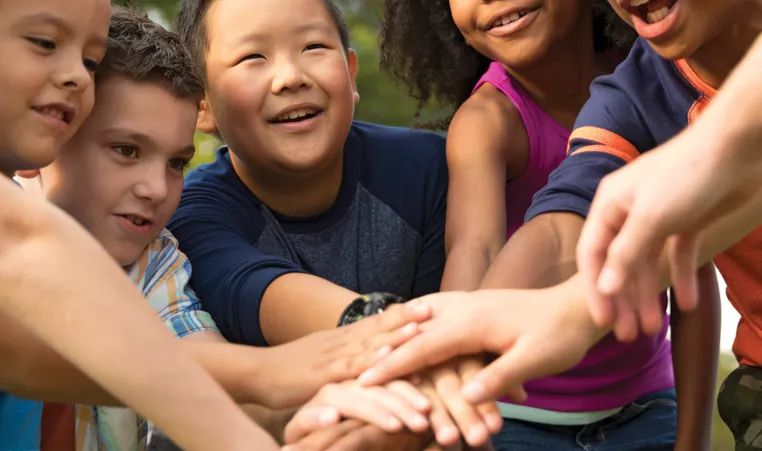 Kids huddle and put their hands together while playing a game.