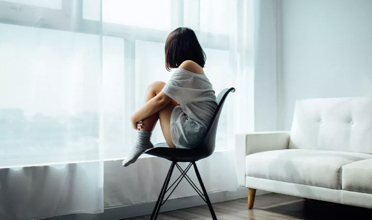 Photo of a woman sitting in a chair looking out the window