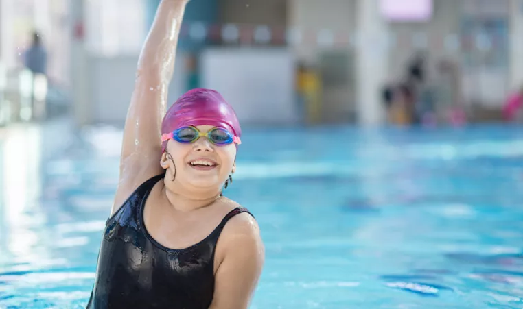 Photo of girl smiling and pumping her fist in the air in a swimming pool